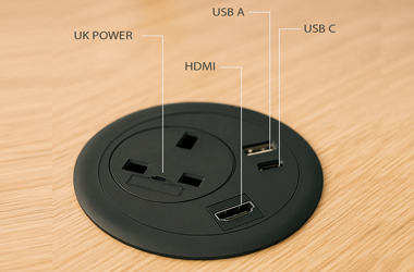 Round grommet-mounted PDU with power sockets, USB charging, and data ports for office desks